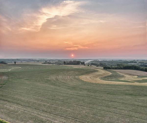 Person stretching gently outdoors during a beautiful sunrise.